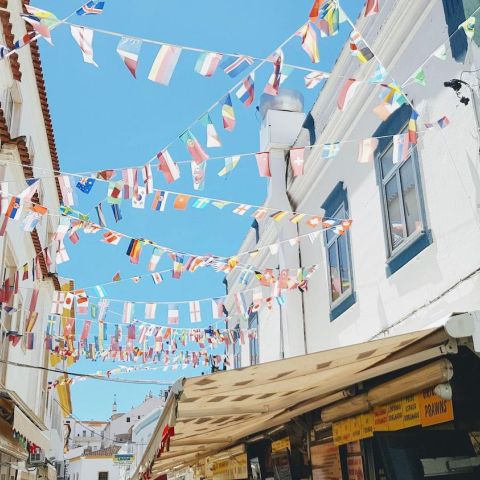 Flags on strings hang between white buildings.